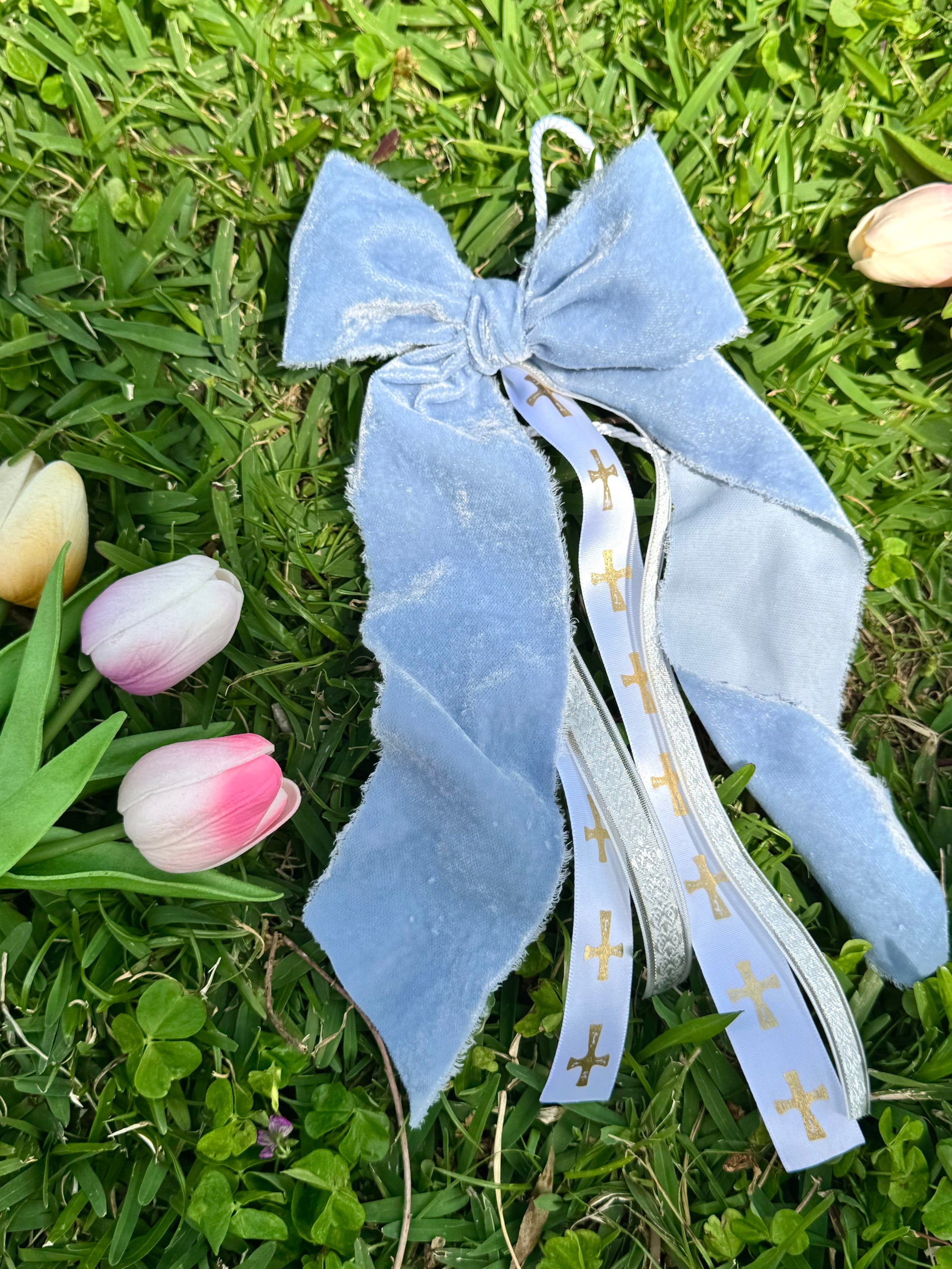 Blue decorative bow with ribbons on grass with tulips