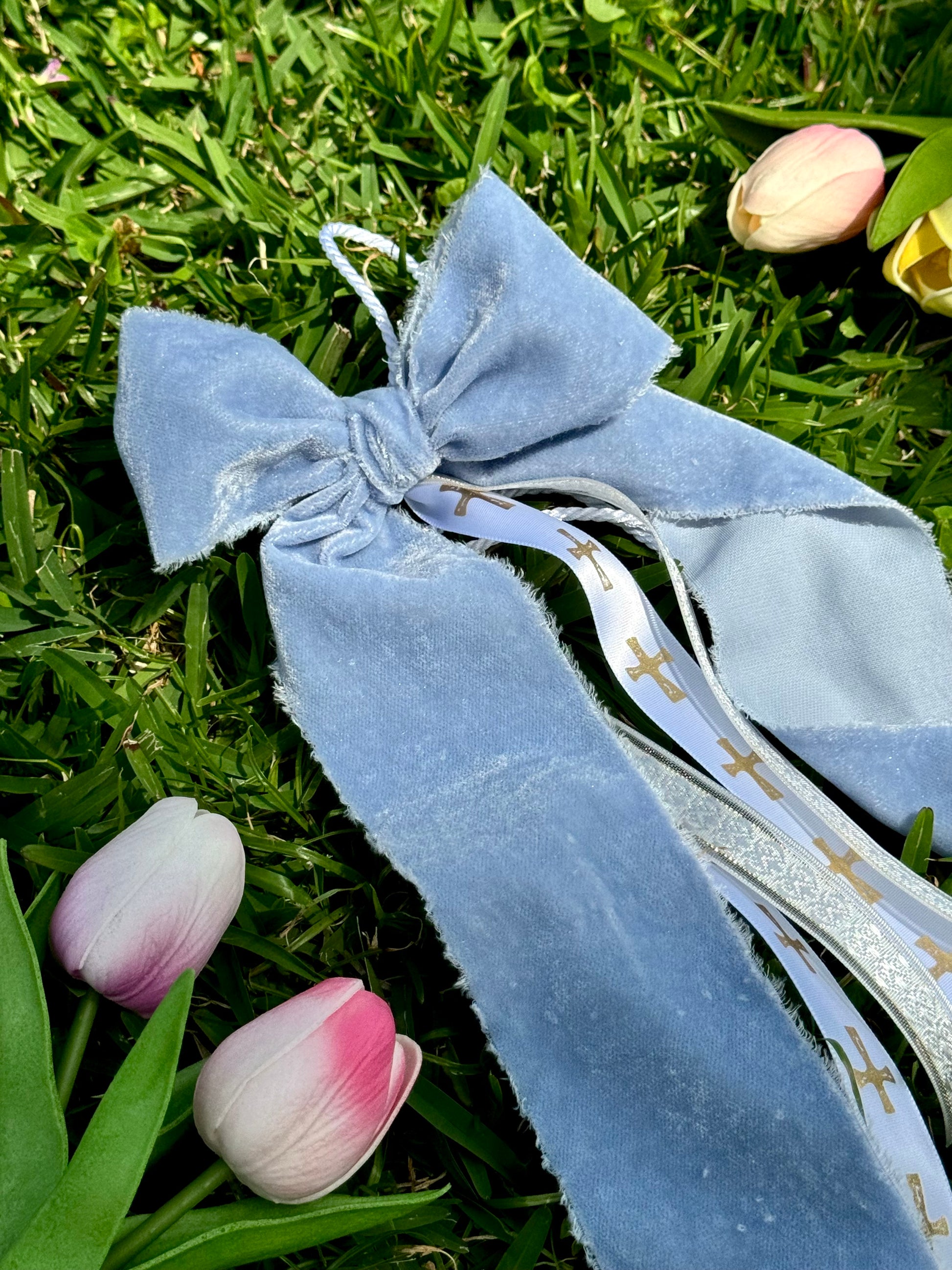 Blue ribbon with decorative elements on grass with tulips