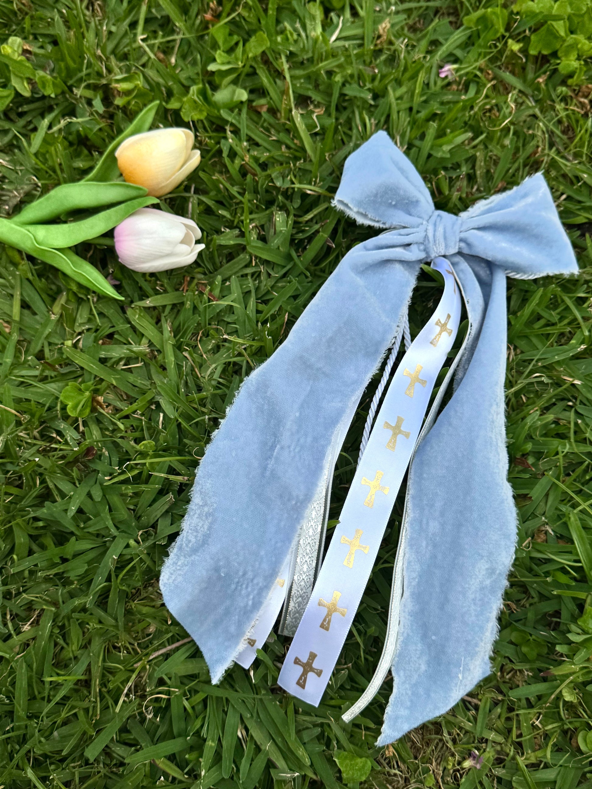 Blue ribbon with gold crosses on grass with tulips